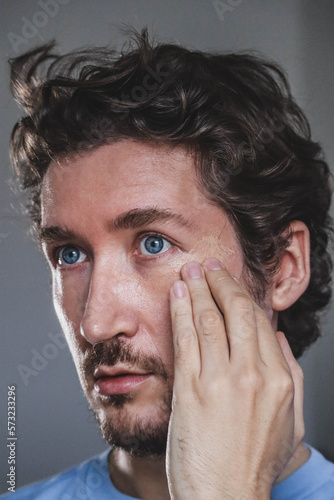 Handsome young man applying foundation to his face