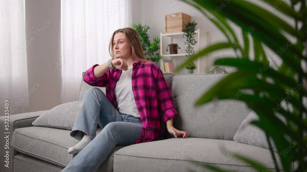Young woman talking on smart watch while sitting on couch Young woman talking on smart watch while sitting on couch