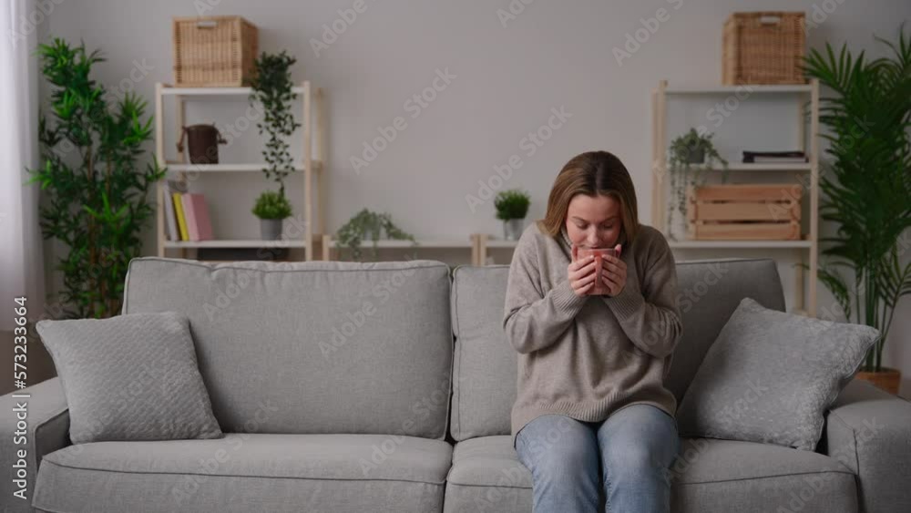 Young woman relaxing on sofa with cup of coffee or tea. Young woman relaxing on sofa with cup of coffee or tea.