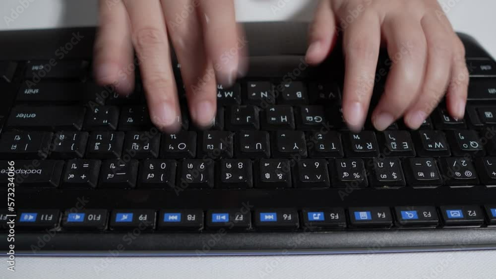 Close up select focus of woman hands speed typing on a black computer keyboard, Woman working with thai language keyboard at night in Thailand.