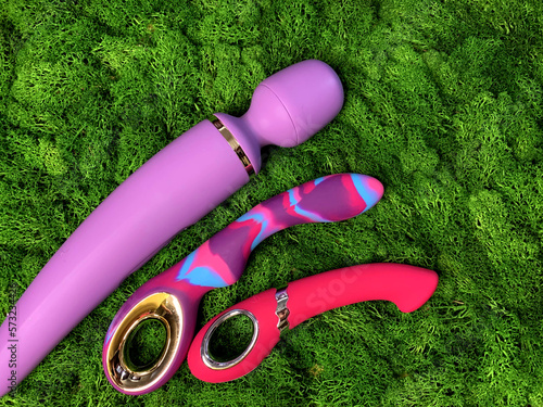 Three vibrators on green background. Sex shop asortment. Sex toys. Flat lay photo