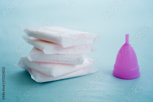 Menstrual cup and pads on a blue background, concept of critical days
