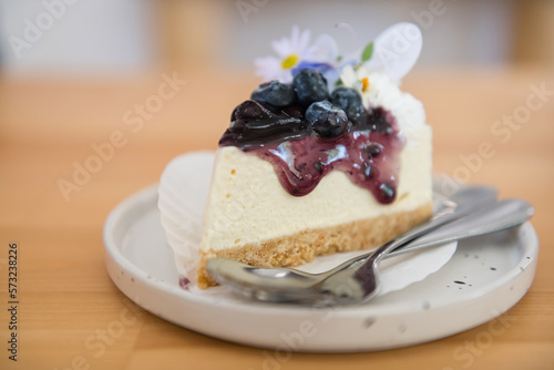 Cheesecake with fresh blueberries and flower decor on wooden table