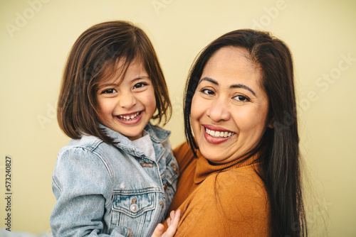 Happy southeast Asian mother with her daughter smiling in front of camera - Lovely family portrait