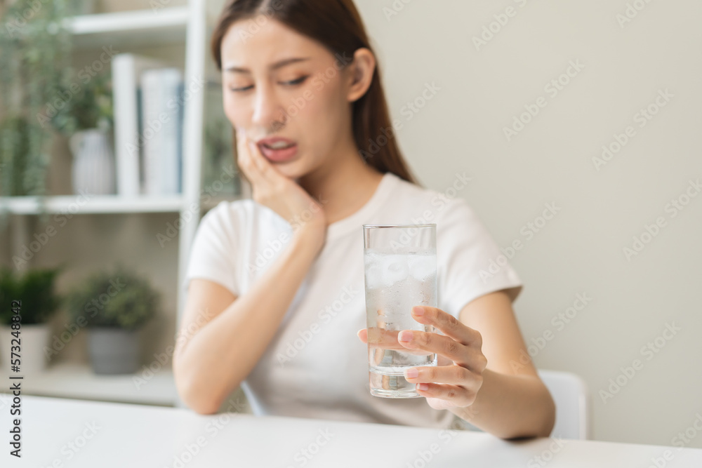 Suffering from toothache, asian young woman, girl touch cheek, face expression ache or feel pain, sensitive molar teeth, hand holding glass of water with ice, inflammation when drink cold, healthcare. Suffering from toothache, asian young woman, girl touch cheek, face expression ache or feel pain, sensitive molar teeth, hand holding glass of water with ice, inflammation when drink cold, healthcare.