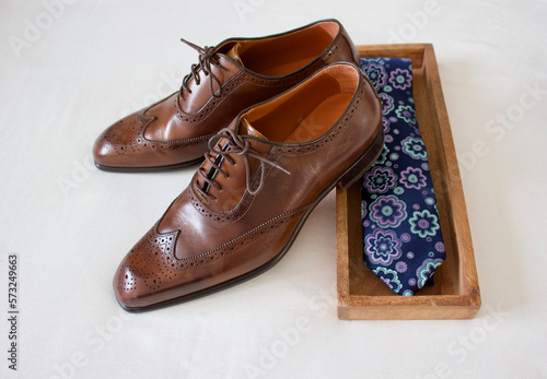 brown man leather shoes with a blue necktie in a wooden box on a white background, bird's eye view