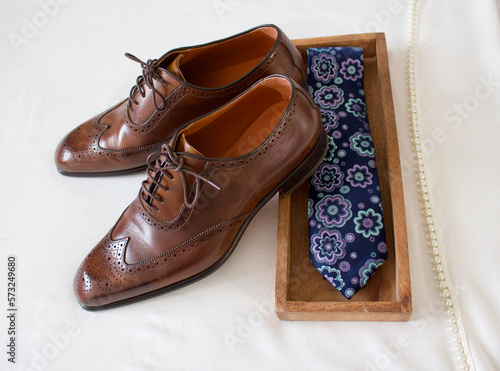 brown man leather shoes or brown man business shoes with a necktie in a wooden box on a off white scarf with pearls