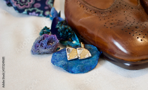 silver golden cufflinks next to brown man leather shoes and necktie