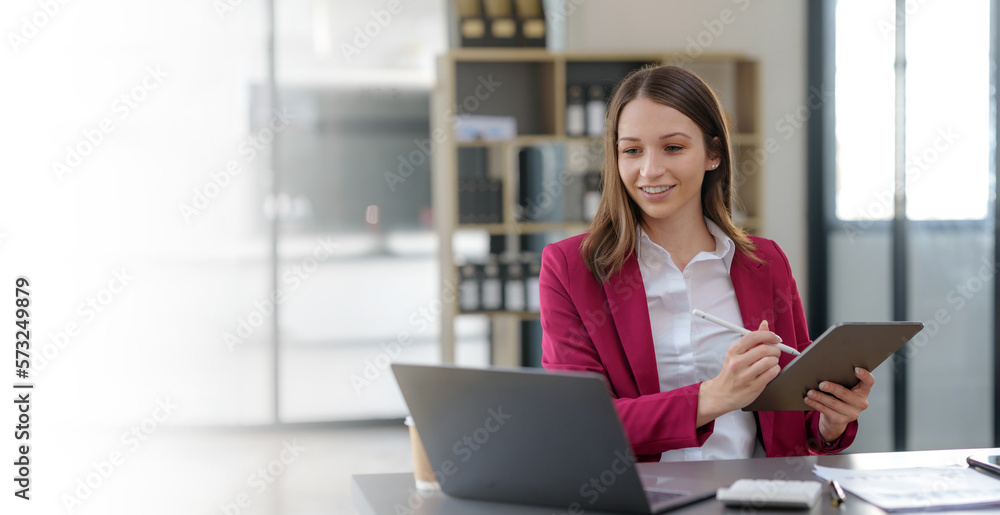 Attractive Asian businesswoman sitting happily using tablet at work and smiling happily. Attractive Asian businesswoman sitting happily using tablet at work and smiling happily.