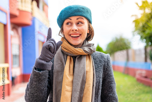 Brunette woman at outdoors intending to realizes the solution while lifting a finger up © luismolinero