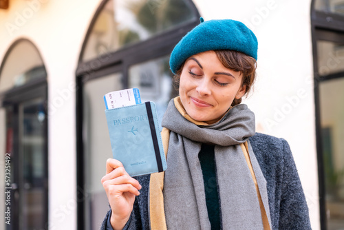 Brunette woman holding a passport at outdoors with happy expression © luismolinero