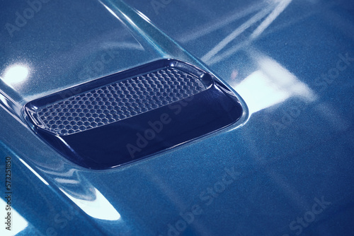 detail of sport car with blue metal hood and air flow intake ornament photo