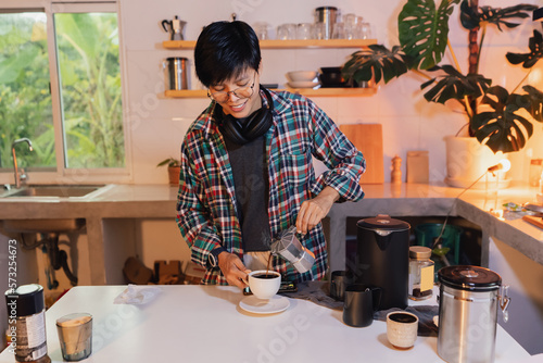 man using Italian moka coffee pot, barista pouring espresso coffee into cup with equipment, kettle roasted coffee beans on background white marble kitchen bar decorated with wooden shelf and pot plant