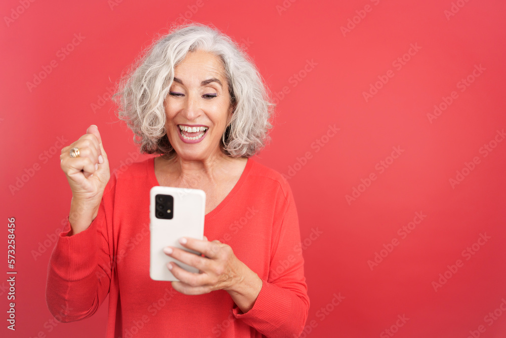 Mature woman celebrating while using the mobile phone