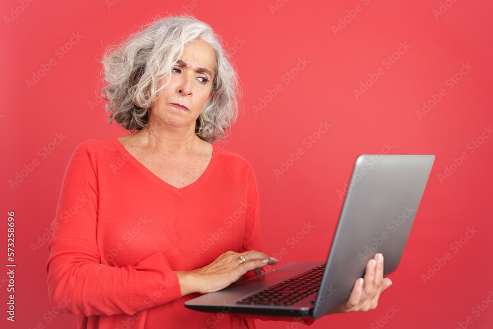 Worried mature woman standing and using a laptop Worried mature woman standing and using a laptop
