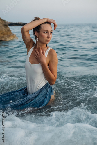 Beautiful girl posing in the sea waves in evening. fashion photo shoot in nature photo