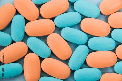 Pattern, blue and pink vitamins in pills for men and women on blue paper flatlay background. The concept of differences in the needs of the female and male gender