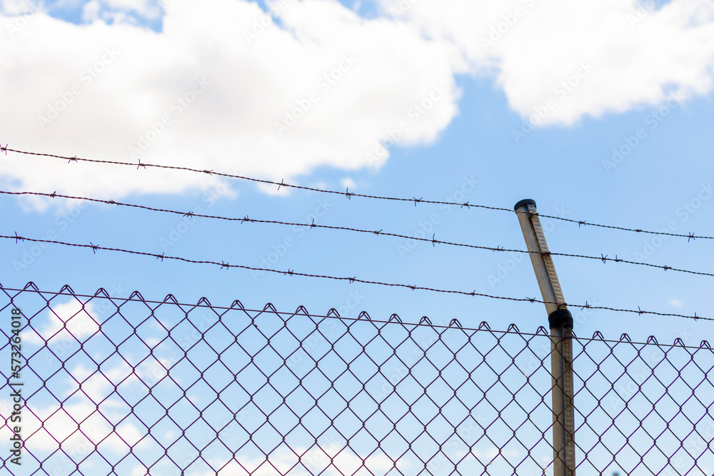 Metal fence with rusty and dangerous barbed wire, an obstacle commonly used to preserve private property Metal fence with rusty and dangerous barbed wire, an obstacle commonly used to preserve private property