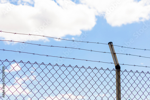 Metal fence with rusty and dangerous barbed wire, an obstacle commonly used to preserve private property