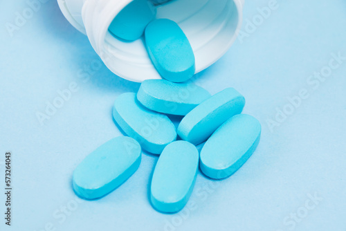 White plastic jar with pills on a blue paper background