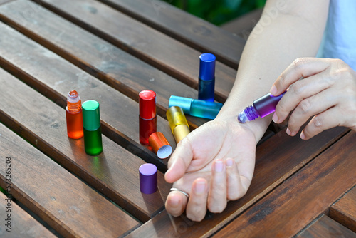 Woman use violet herbal natural essentials oil roll on her wrist, healing crown chakra. Mindfulness spiritual living. New age self care, spirituality awakening.
