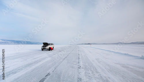 A driver inflates his tires on the frozen lake Baikal © muratart