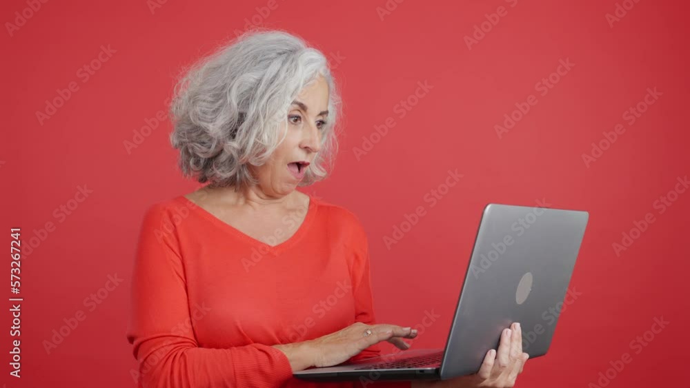 Surprised mature woman standing and using a laptop Surprised mature woman standing and using a laptop