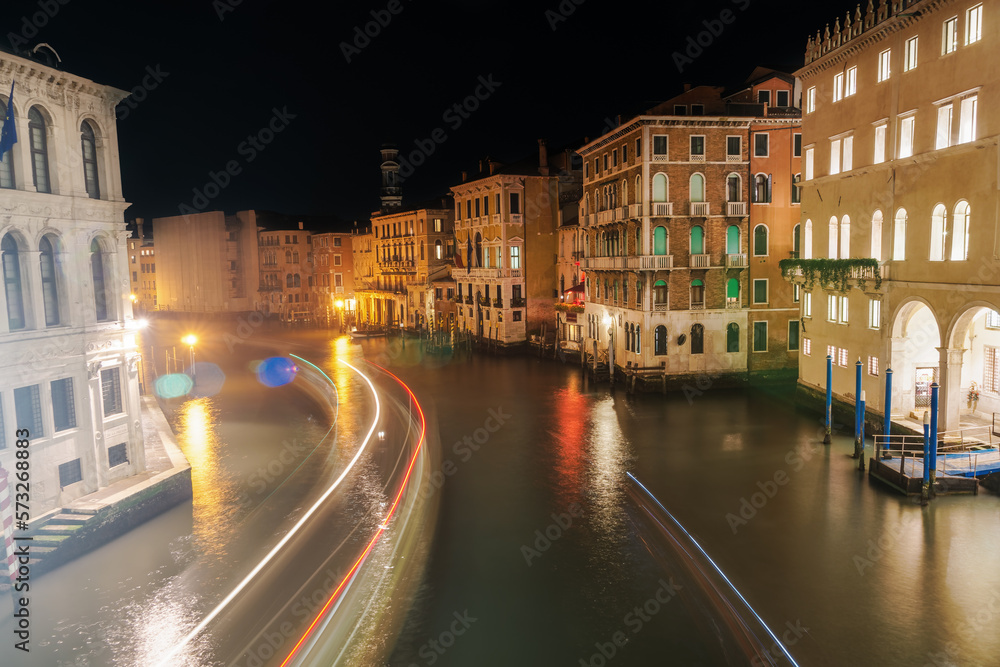 Venice, Italy Grand Canal night view of traditional low-rise buildings and wooden wharf pilings, seen from Rialto Bridge.