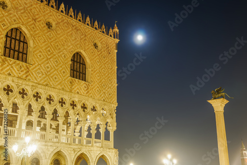 Venice Italy night view of illuminated Palazzo Ducale landmark, 1340 Doges Palace built in Venetian Gothic style, with lion Column of San Marco at St. Marks square.