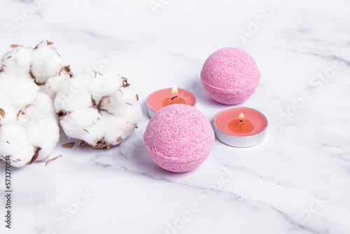 Pink bath bombs, candles and cotton flowers. Bath salts