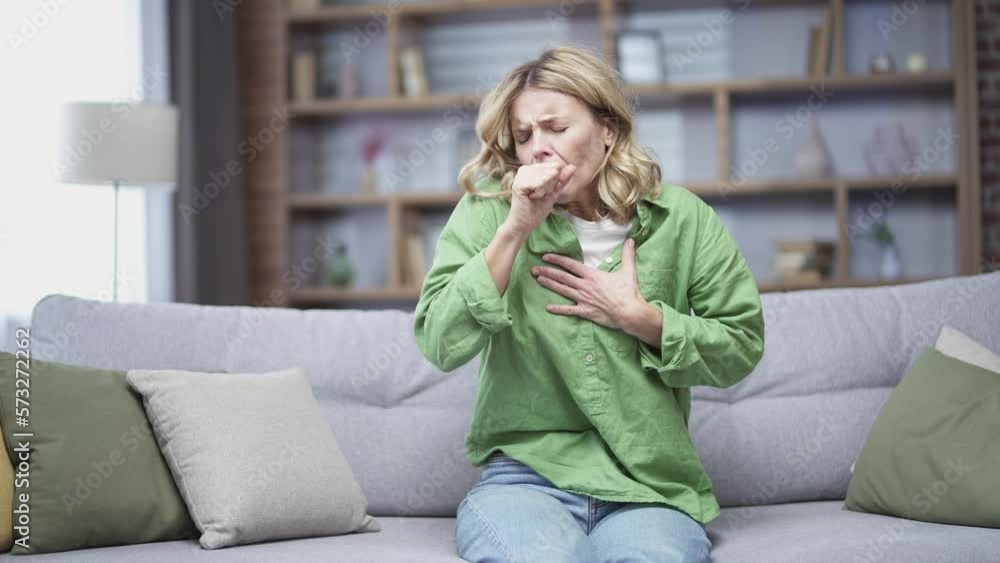 Allergic mature woman coughing because she has seasonal allergies sitting at home. First