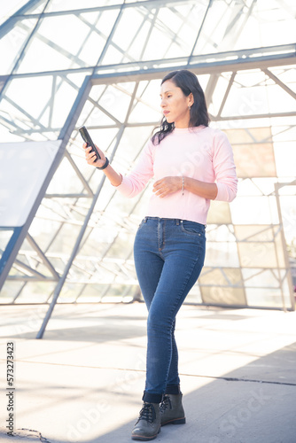 mujer latina urbana con smartphone, hablando y tomado selfie