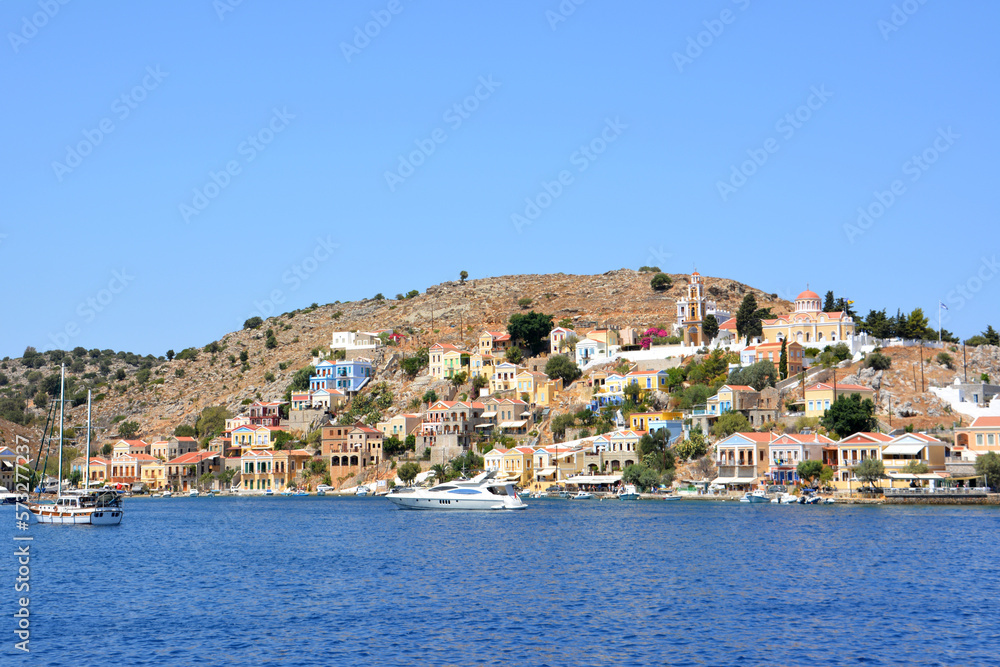 Symi island with hills, town and waterfront with boats on the aegean sea