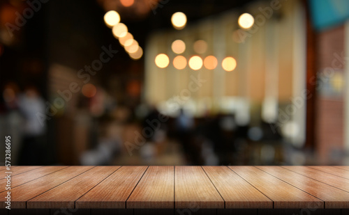 Empty wooden table top with lights bokeh on blur restaurant background.