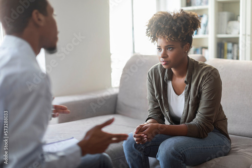 Unhappy black millennial woman listening to psychotherapist