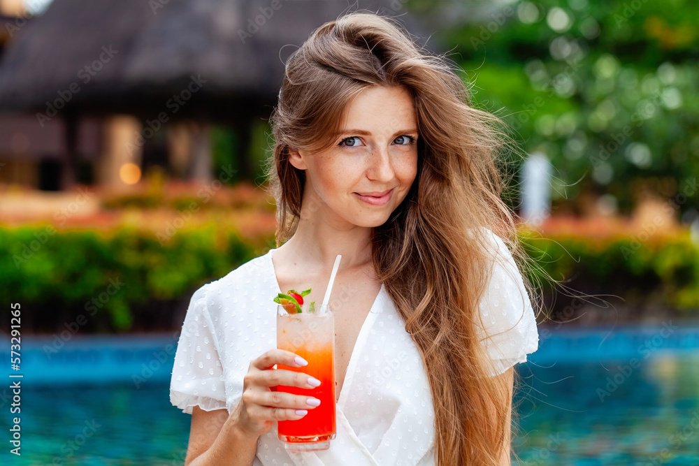 Happy smiling woman drinking tropical cocktail near swimming pool Happy smiling woman drinking tropical cocktail near swimming pool