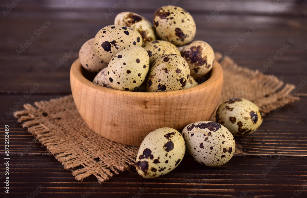 Quail eggs in a wooden bowl on a wooden background.Close-up.
