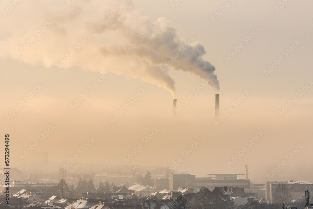 Smoking industrial chimneys emitting fine dust and carbon dioxide over Graz in Austria on a foggy winter morning