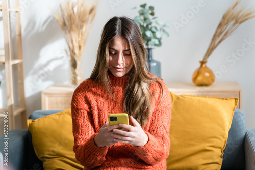 Young woman using smartphone in living room