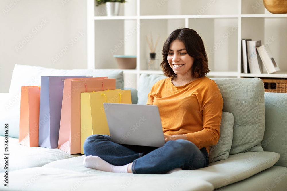 Smiling Young Arab Woman Shopping Online With Laptop At Home Smiling Young Arab Woman Shopping Online With Laptop At Home