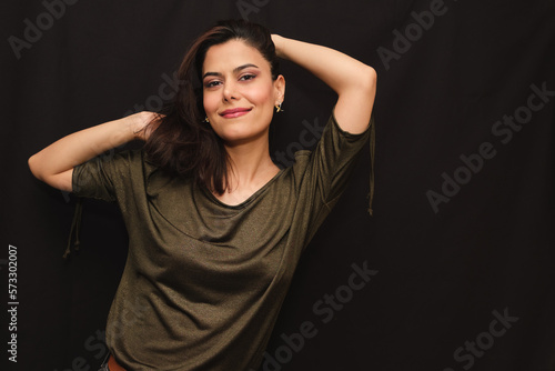 Portrait of smiling woman in green blouse with her hands on her head looking at camera
