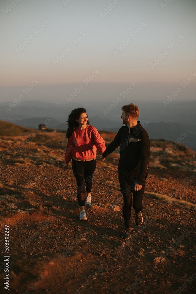 Fototapeta premium Smiling couple walking over green hills