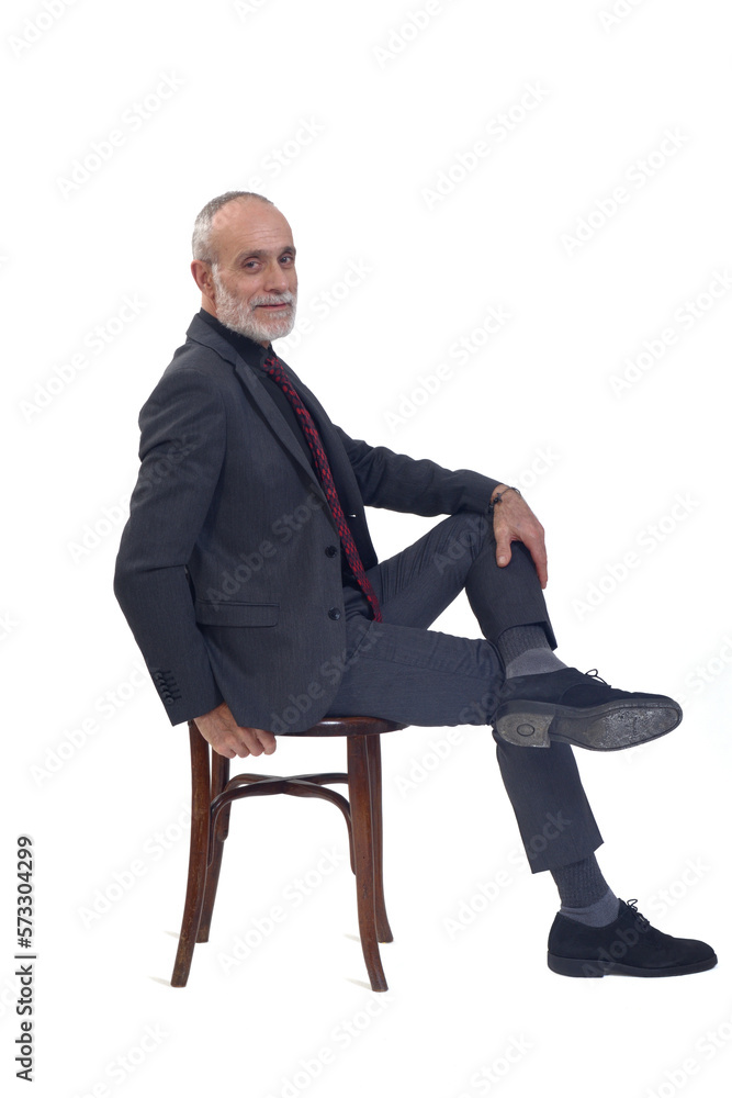 side view of a man sitting on chair with suit and tie and cross legged looking at camera on white background side view of a man sitting on chair with suit and tie and cross legged looking at camera on white background