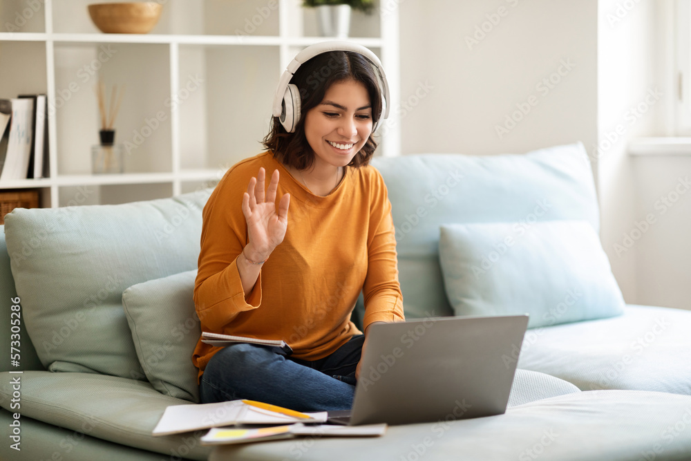 Happy Young Arab Female In Headphones Making Video Call At Home Happy Young Arab Female In Headphones Making Video Call At Home