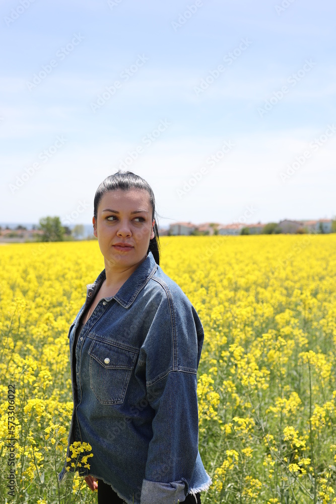 Young beautiful woman in canola field. Freedom, self-confident and youth concept.