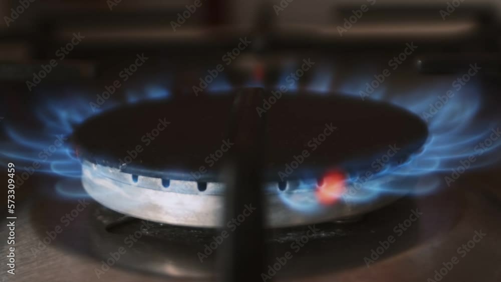 Home gas stove burner starts to burn with blue and red flame close up. Using home gas cooking equipment. Natural fuel flame. Setting fire of a gas burner Home gas stove burner starts to burn with blue and red flame close up. Using home gas cooking equipment. Natural fuel flame. Setting fire of a gas burner