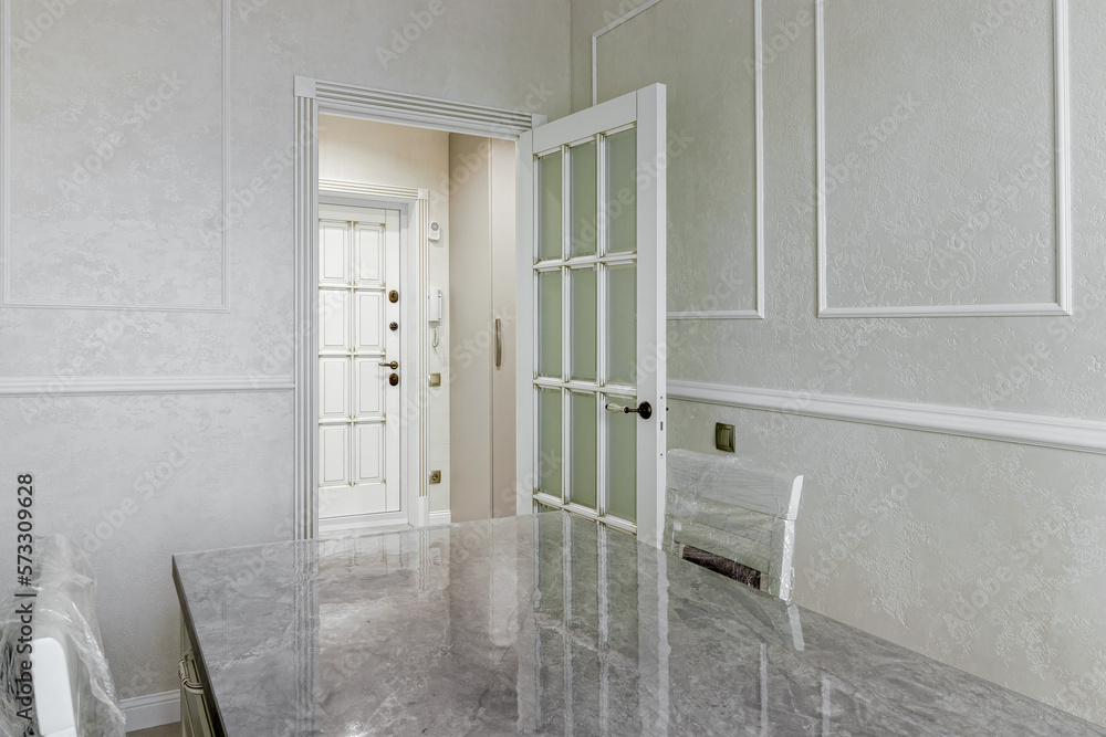 The interior of a stylish house in light colors with white doors with glass.