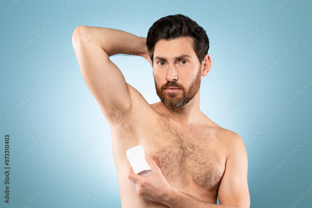 Fresh all day long. Handsome shirtless middle aged man applying deodorant and looking at camera, blue background Fresh all day long. Handsome shirtless middle aged man applying deodorant and looking at camera, blue background