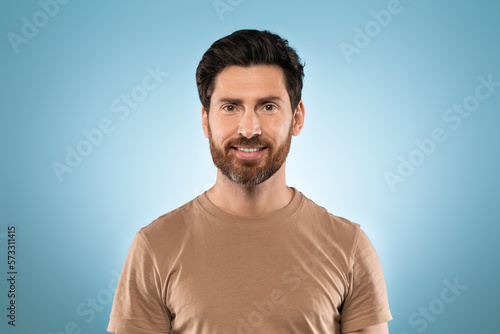 Portrait of happy handsome middle aged man posing isolated over blue studio background and smiling at camera