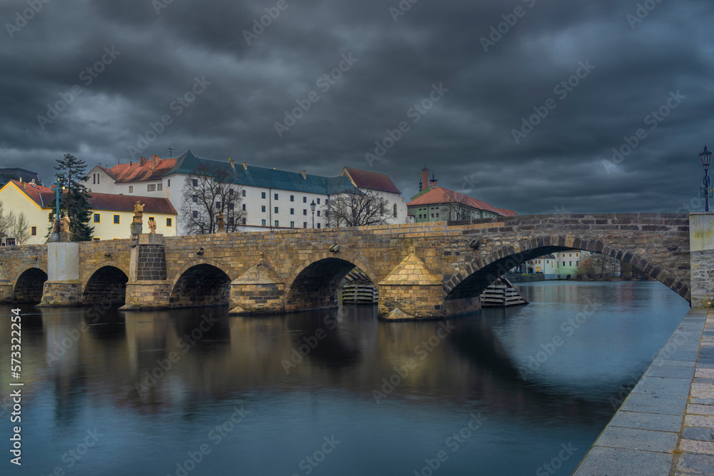 Fototapeta premium Old stone bridge and center of Pisek town in cloudy winter morning
